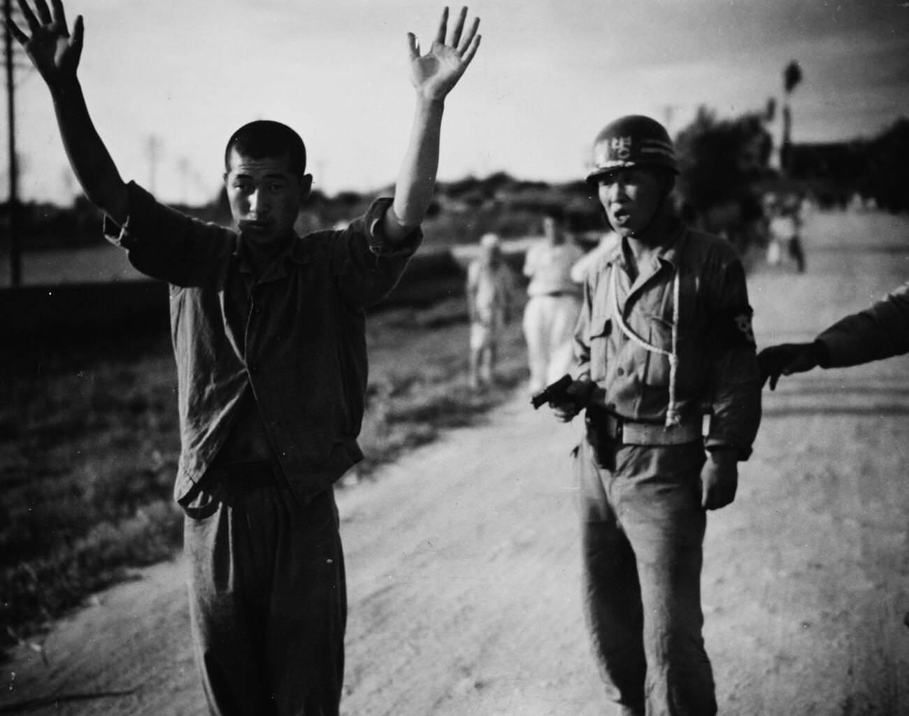 #15 A South Korean military policeman marches a North Korean prisoner of war, 1950.