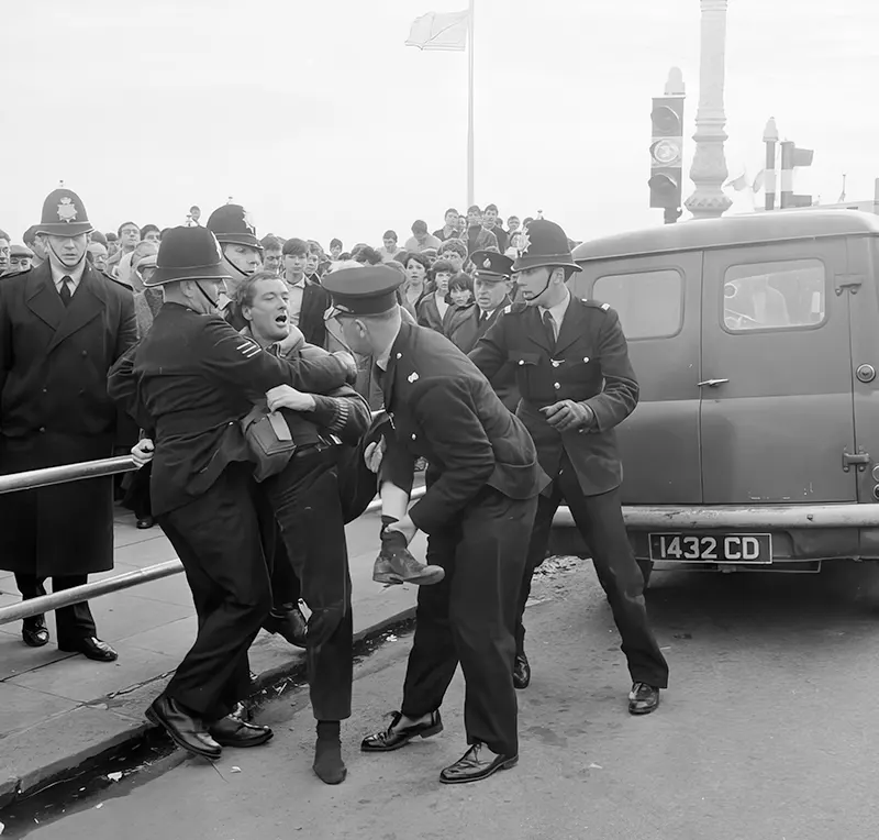 #10 Three police officers drag away a rocker who refuses to stop fighting in Brighton, England, 1965.