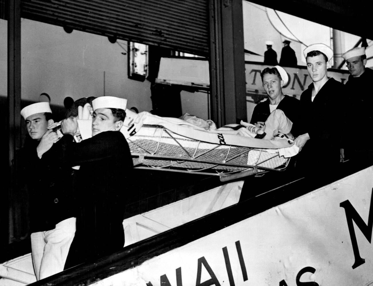 #15 Wounded United States seaman, hit by Japanese sharpnel or bullets in the attack on Pearl Harbor on December 7, being carried to a carrier for transportation to a hospital in San Francisco, 1941.