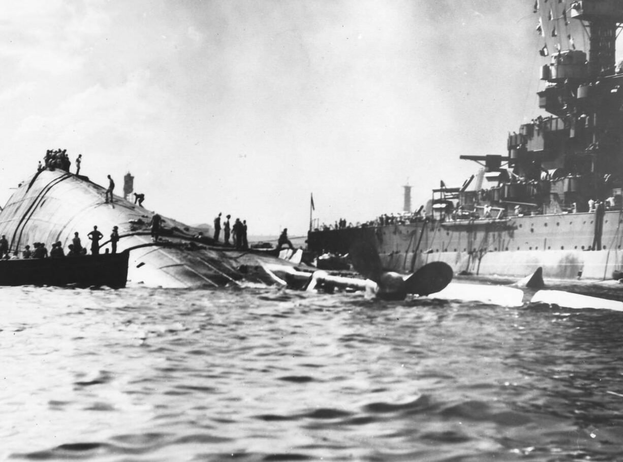 #47 The capsized USS Oklahoma (BB37) and the USS Maryland (BB46) after the Japanese attack on Pearl Harbor, 1941.