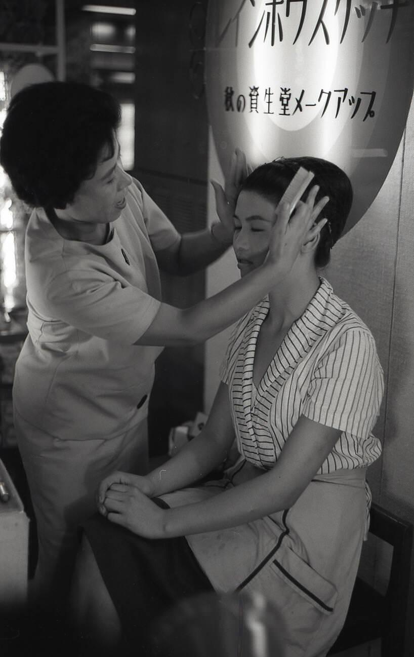 #24 A Shiseido make-up artist touches the face of a young woman during a make-up demonstration, 1958.