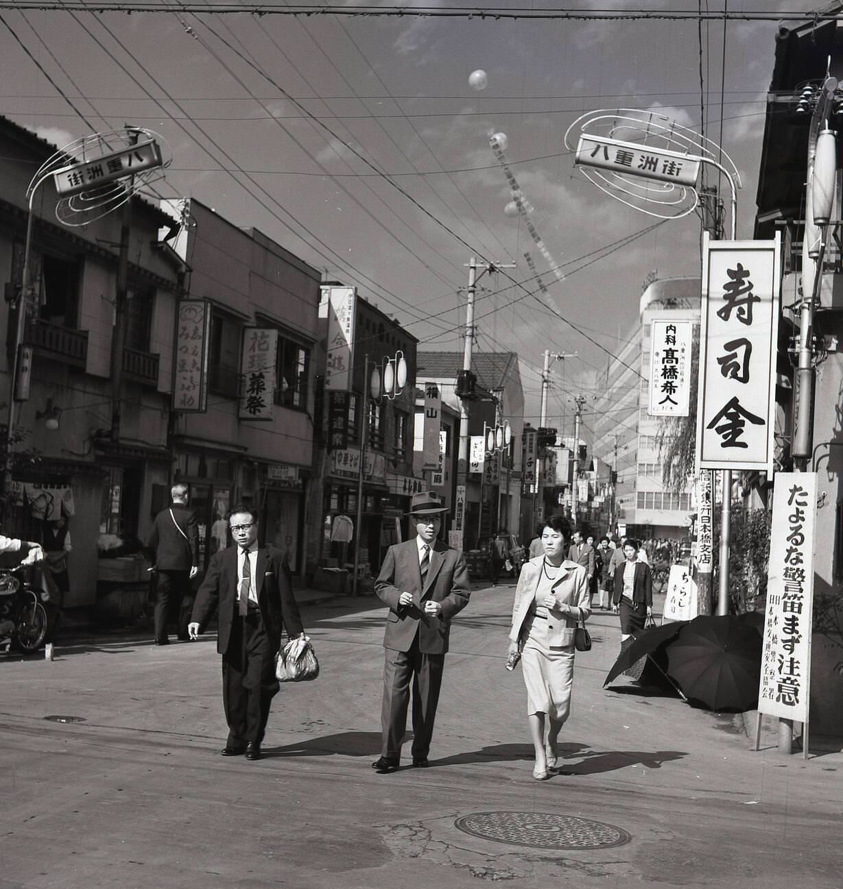#47 Two businessmen and a lady walking through the old town district of Tokyo, 1950s.
