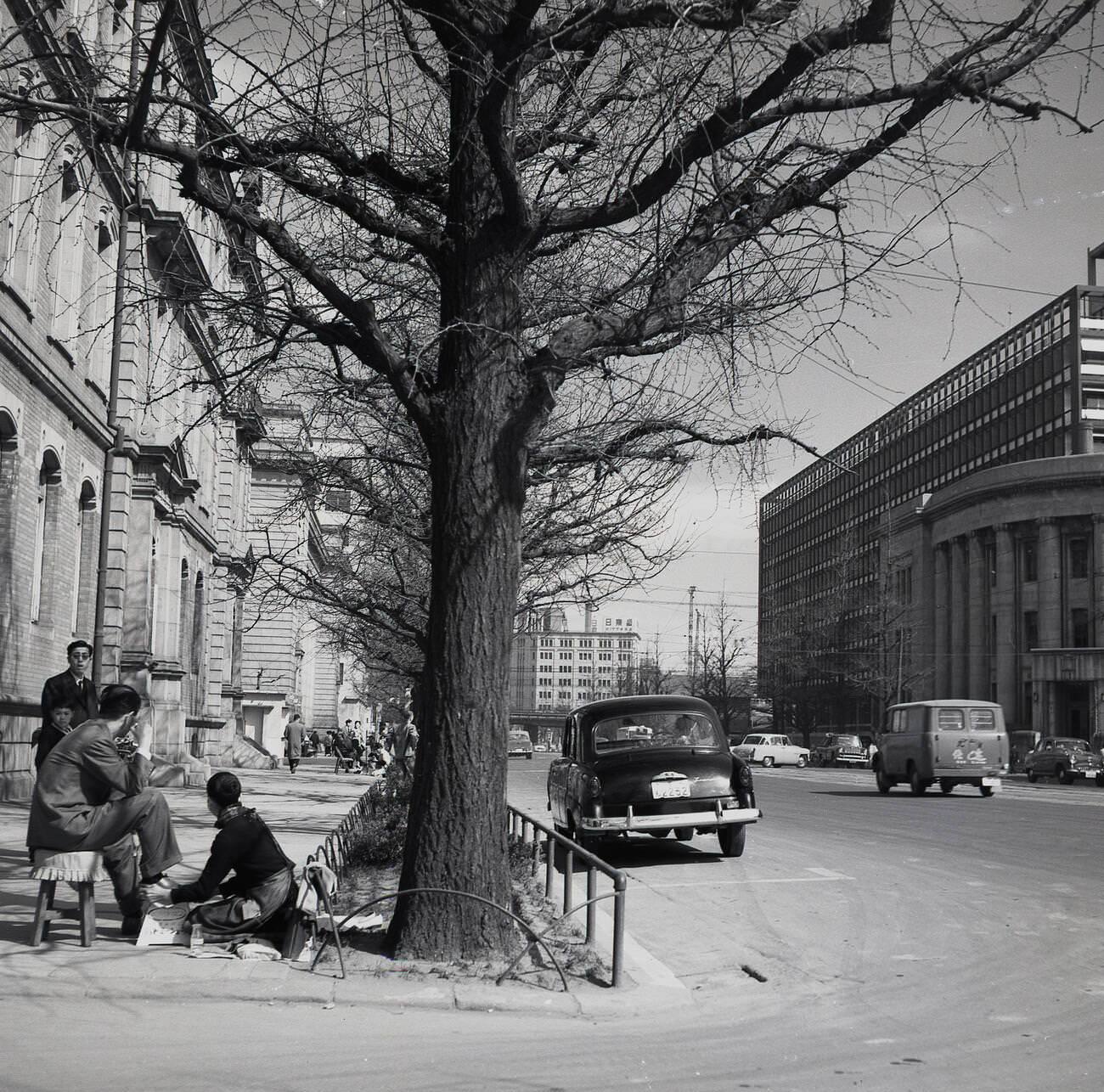 #59 A Japanese businessman sitting on a stool having his shoes shined on a street corner, 1950s.