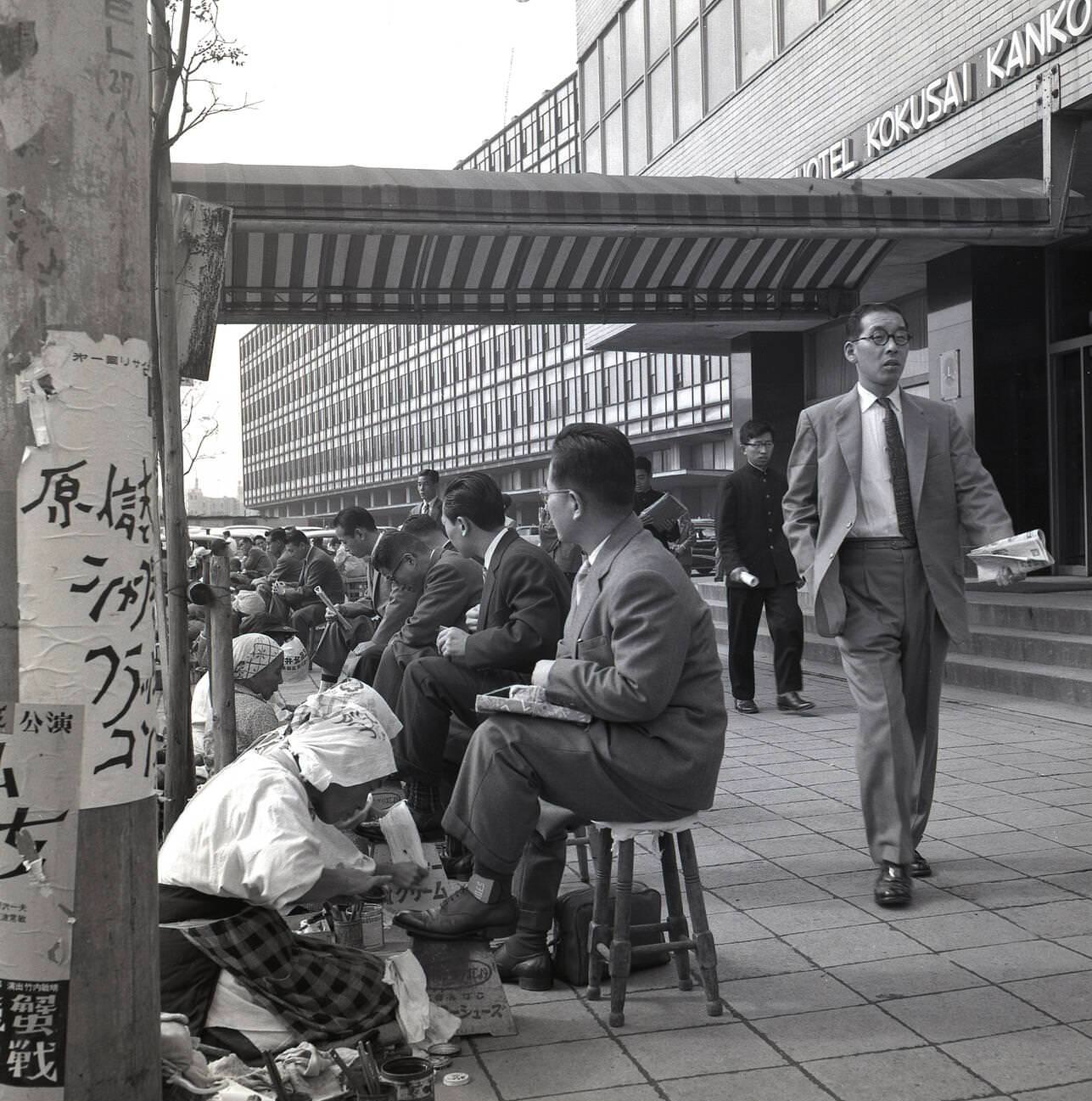 #62 Japanese businessmen sit on little stools having their shoes polished and cleaned, 1950s.