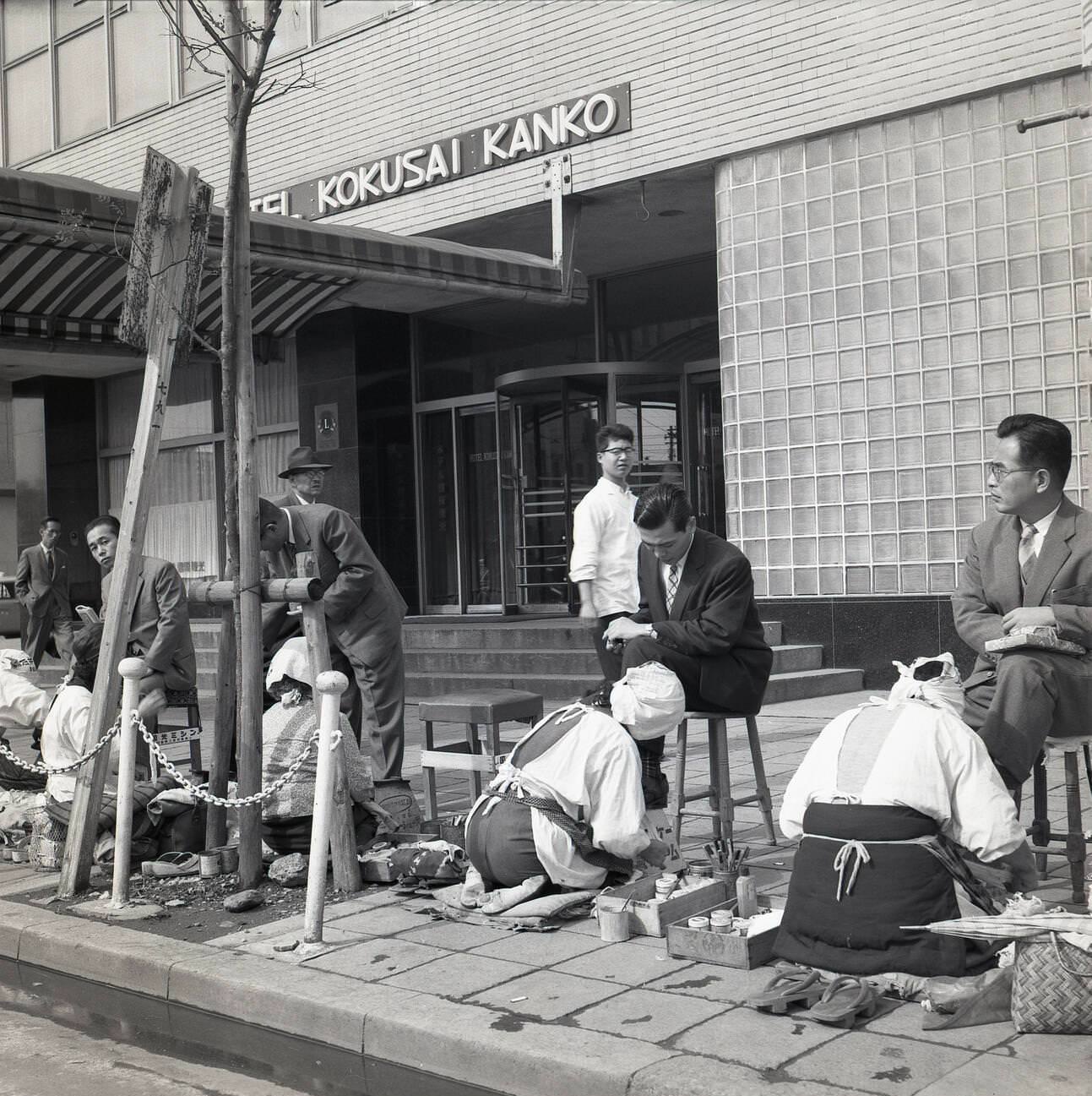 #63 Japanese businessmen sit on little stools having their shoes polished and cleaned, 1950s.