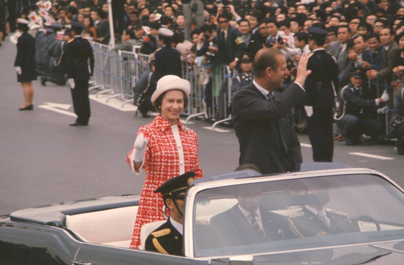 #19 Queen Elizabeth II and Prince Philip, Duke of Edinburgh wave to cheering crowds as the Royal couple proceed in a motorcade in Tokyo.