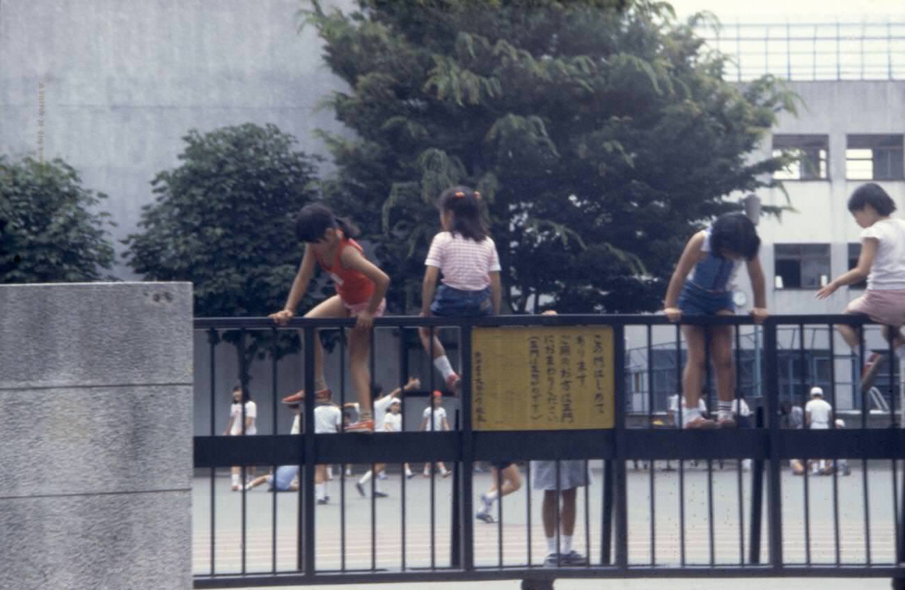#112 Children climb the school fence, Tokyo, 1970s.