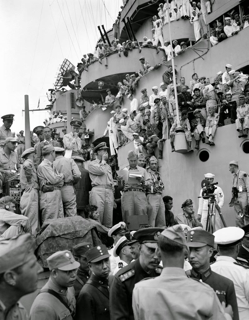 #56 Spectators and correspondents from all over the world watch the formal Japanese surrender ceremony marking the end of World War II on the deck of the USS Missouri, in Tokyo Bay, 1945.