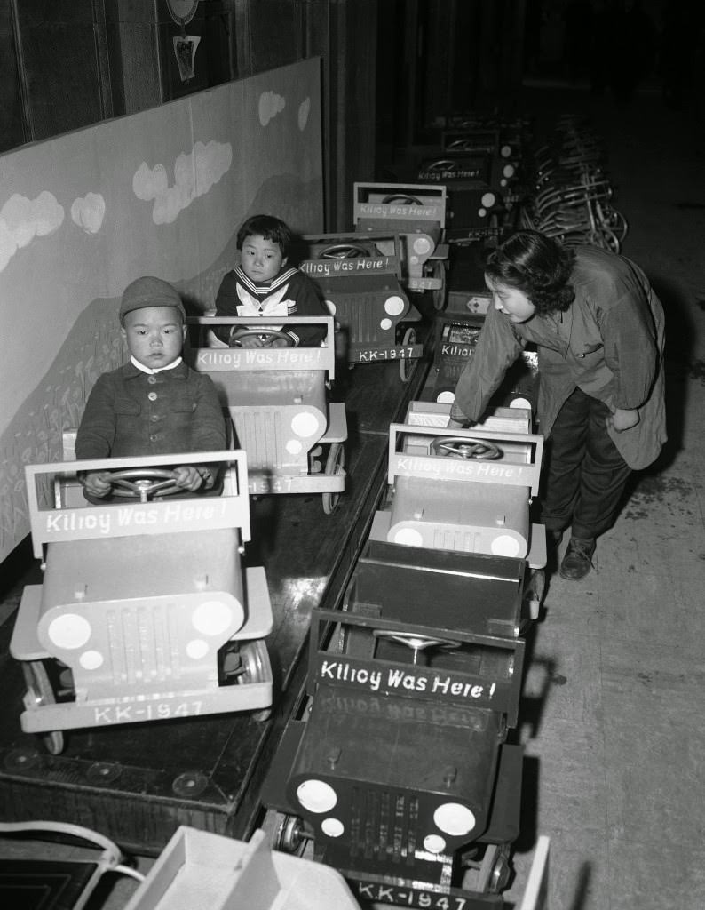 #66 Japanese children, visiting a Tokyo department store, try out toy jeeps bearing the slogan, “Kilroy was here,” 1947.