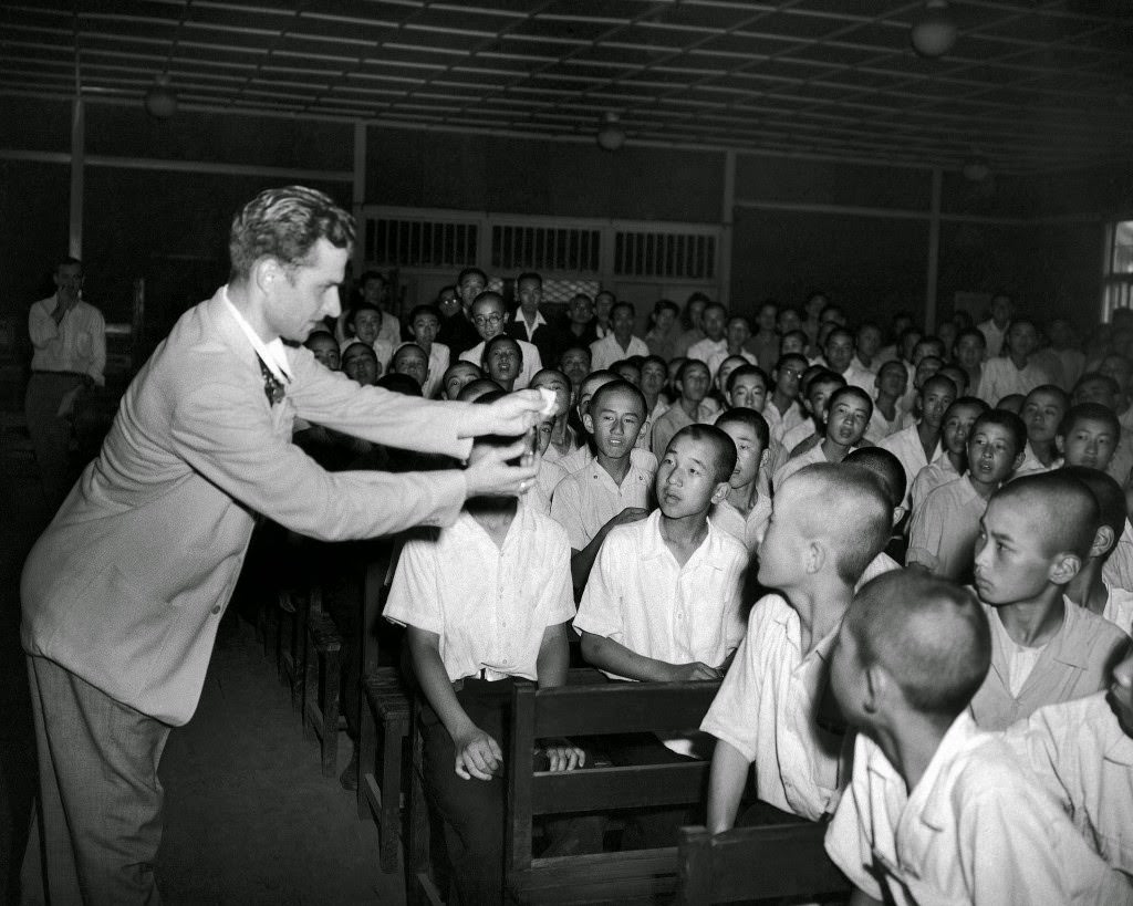 #90 Students at the Peers’’ School in Tokyo are mystified as Jacob Tropp of Brooklyn, New York, amateur magician, makes a 50 cent piece, wrapped in tissue paper, disappear in a burst of flame, 1948.