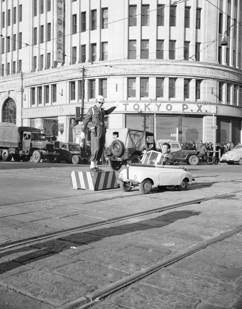 #95 The brainchild of a former kamikaze pilot, this midget auto gets its power from a 30-volt battery. It is shown passing the main intersection of the Ginza Street in Tokyo, 1947.