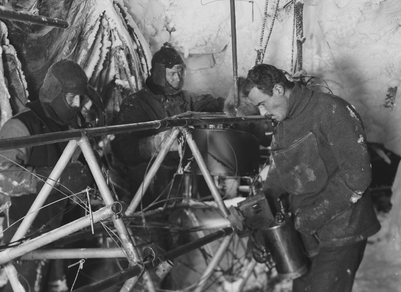 #35 Bickerton repairs the Air-tractor in the Hangar (left to right Bage, Ninnis, Bickerton0, Cape Denison, Antarctica, 1912-1913, by Frank Hurley