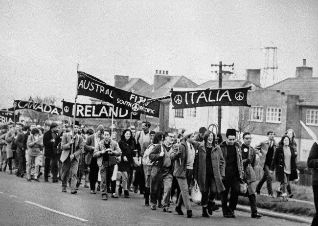 #23 Foreign groups (from Italy, Fiji, Australia, Canada, and Algeria) are in the column of marchers as some 10,000 supporters of the Campaign for Nuclear Disarmament set out from Reading, Berkshire, on the second leg of their protest march from Aldermaston to London, 1962.