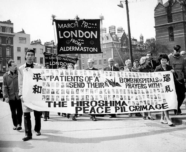 #25 Two survivors of the Hiroshima atomic bomb, 29-year-old nurse Miyoko Matsubara and law student Hirosama Hanabusa, 18, join the column of British nuclear disarmers as the demonstrators file into London’s Hyde Park for the mass rally climaxing their Easter March from Aldermaston, 1962.