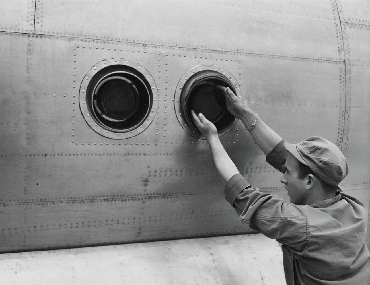 #5 American Private first class Marvin L Cooper tightens the filter on the outer lens surface of two bomb bay K-18 cameras, mounted on an F-13 camera aircraft at Roswell Army Air Field, New Mexico, 1946.