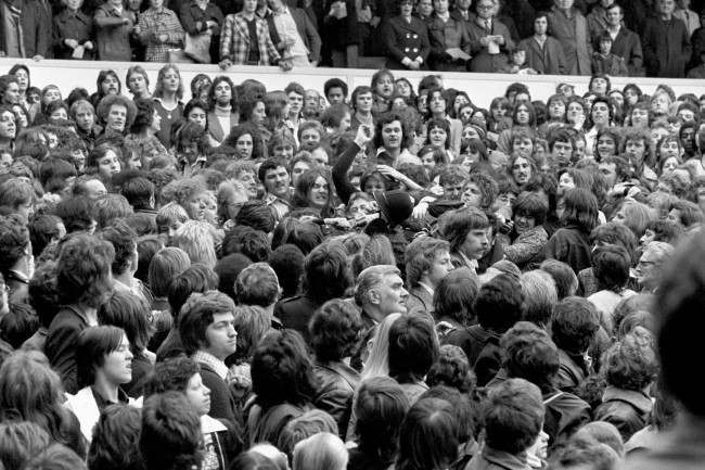 A policeman’s helmet goes flying as he wades into the crowd, 1970s.