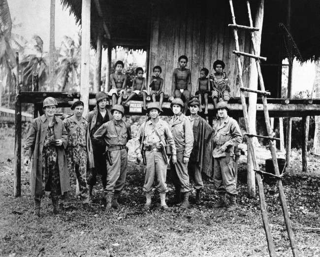 #21 War correspondents covering the allied occupation of Kiriwina Island line up in front of a native hut. 1943