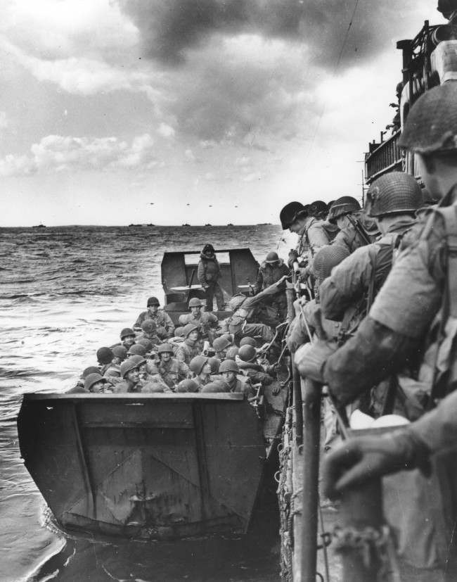 #10 American assault forces hurtle over the side of a Coast Guard LCI into a landing barge, 1944.