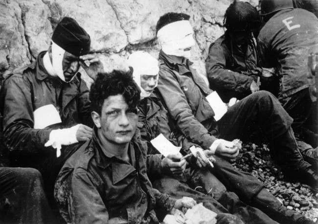 #28 Men of the American assault troops of the 16th Infantry Regiment, injured while storming a coastal area code-named Omaha Beach, wait for evacuation, 1944.