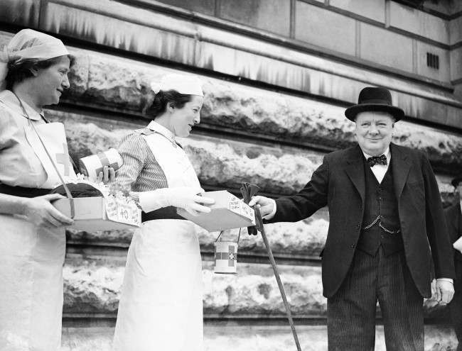 #40 The Prime Minister, Winston Churchill, buying a Red Cross flag from a St. John’s Ambulance nurse, 1944.