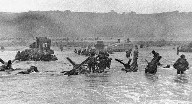#46 Some of the first assault troops to hit the Normandy, France beachhead take cover behind enemy obstacles to fire on German forces, 1944.