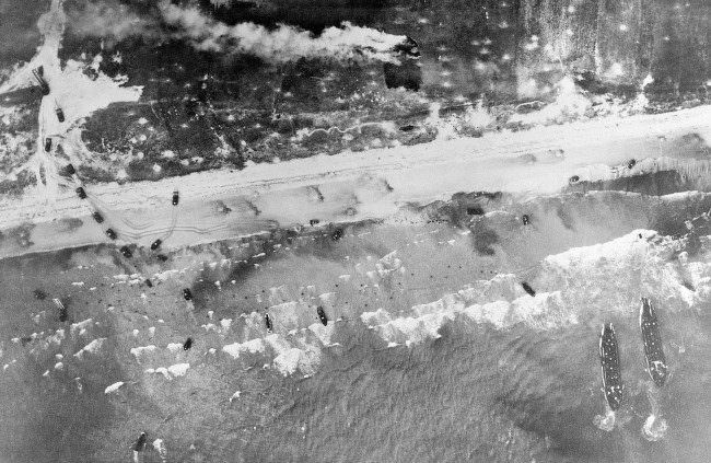 #48 Allied troops come ashore in the surf and vehicles start inland on the German-held beach of Normandy, France, 1944.