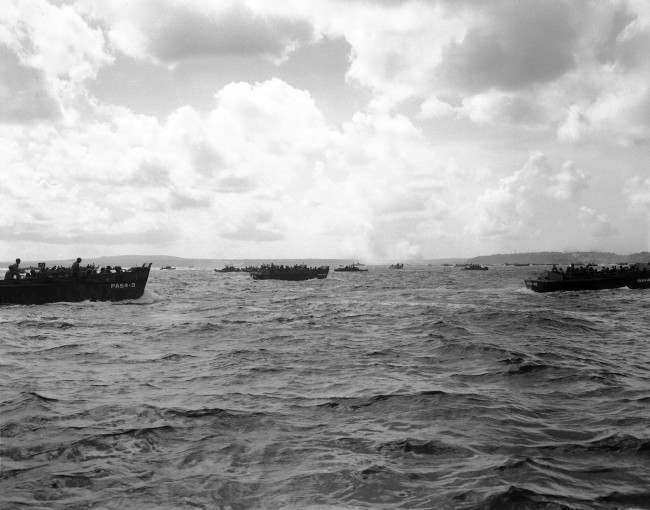 #49 Smoke from Agana torpedo bomber targets are seen in the distance as landing craft race toward the Asan shore at Guam, 1944.