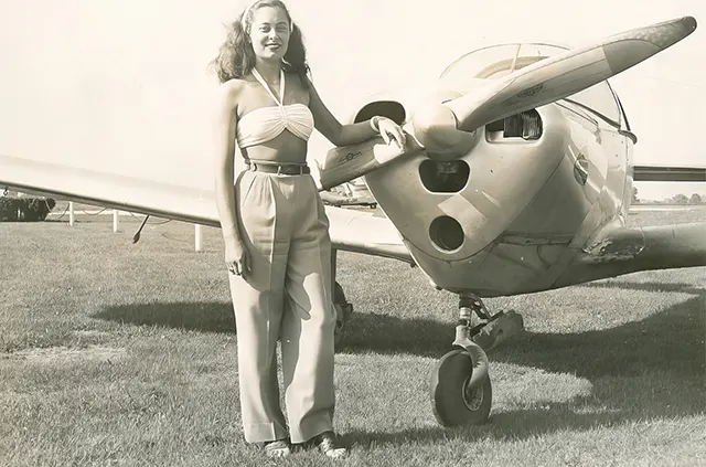 #26 A young woman poses with an airplane, 1940s