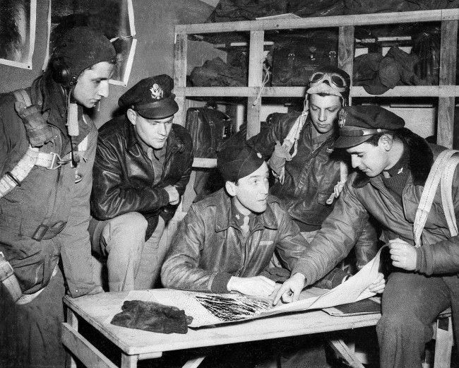 #16 Major Jimmy Stewart talks over the final details of a mission with flyers about to take off, from left to right: Sgt. Keith M. Dibble of Rixford, Pa.; first Lt. Roger Counselman of Meadville, Pa.; Stewart; Sgt. Joseph T. Fiorentino of Philadelphia, Pa.; and second Lt. A.E. Lensky of Monessen, Pa., April 19, 1944, in England during World War II.