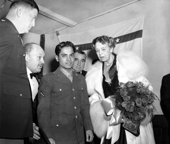 #18 Eleanor Roosevelt holds a bouquet of roses as she stands with Sabu, the ÂElephant BoyÂ of movie fame, and now a soldier attached to Fort Meade, Md., at the president’s birthday ball celebration at a USO post in the YMCS in Washington on Jan. 29, 1944.