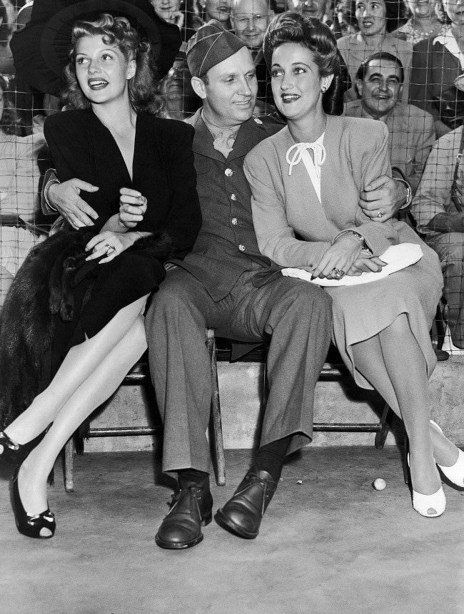 #6 Dressed in the uniform of a technical sergeant of the U.S. Army Air Forces which he joined, Gene Autry, cowboy movie actor, found himself as popular with a pair of glamorous actresses as he is with the kids of the nation when he appeared at a benefit party staged by film actress Marion Davies, Aug. 9, 1942. With him are Rita Hayworth, left, and Dorothy Lamour.