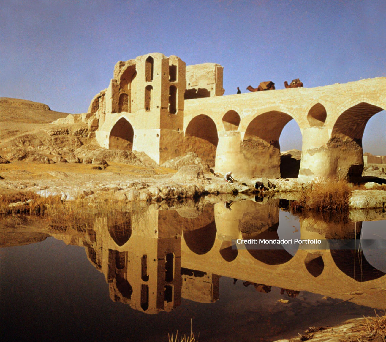 #42 A caravan of camels crossing the Sharestan bridge reflected in the water, Iran, 1960s.