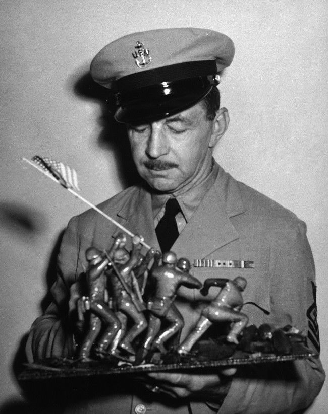 #13 AP photographer Joe Rosenthal, holds a wood carving depicting his famous photo of the flag raising at Iwo Jima, 1945.