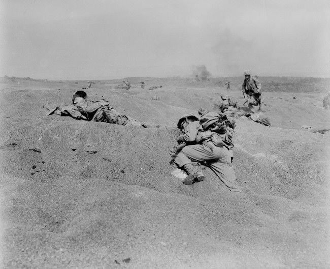 #15 Two U.S. Marines, slumped in death, lie where they fell on Iwo Jima, among the first victims of Japanese gunfire as the American conquest of the strategic Japanese Volcano Island begins, 1945.
