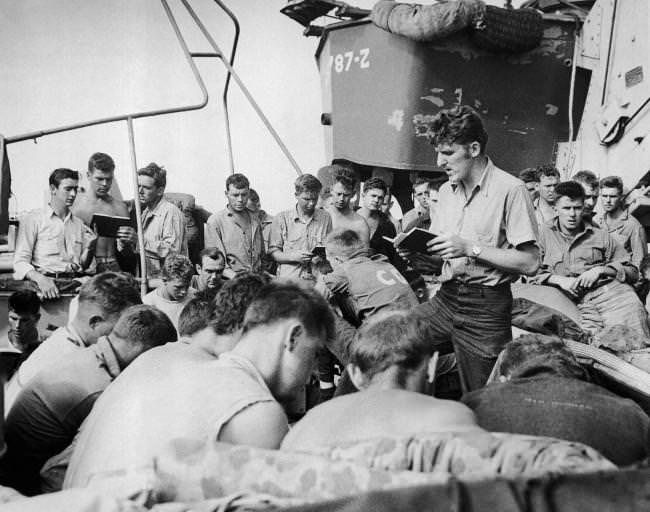 #20 Coast Guardsman Charles R. Roth, leads the singing of hymns on an LST headed for Iwo Jima, the day before the invasion, 1945.