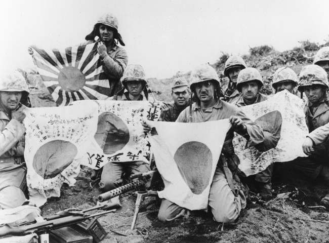 #26 U.S. Marines of the 5th Division pose with captured Japanese battle flags, at Iwo Jima, 1945.