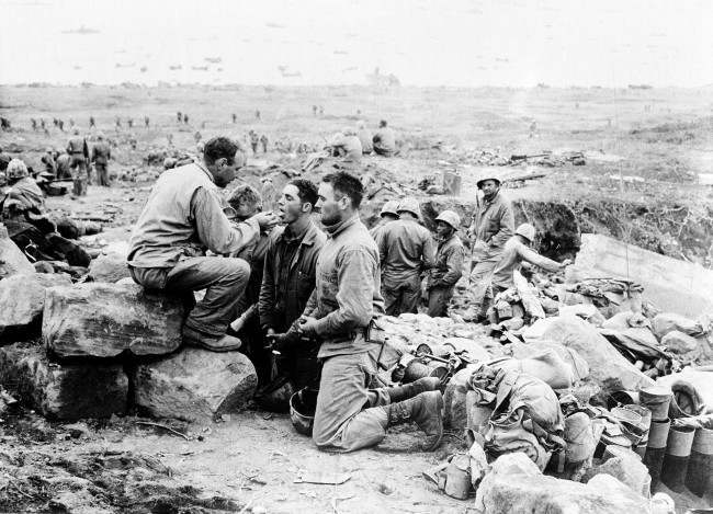 #27 U.S. Marines receive communion from a Marine chaplain on Iwo Jima, the largest of the Japanese Volcano Islands, 1945.