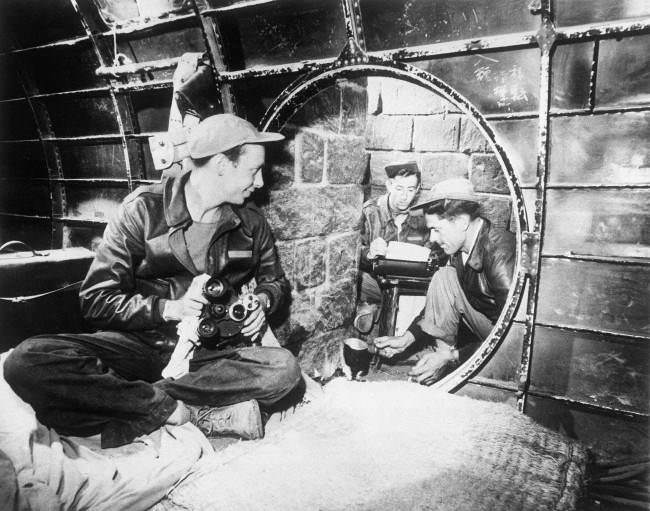 #35 Twelve feet below the surface near an Iwo Jima airstrip, Japan, three 7th AAF combat cameramen establish their headquarters in a former Japanese underground quarters made of a wrecked bomber fuselage and stone blocks, 1945.