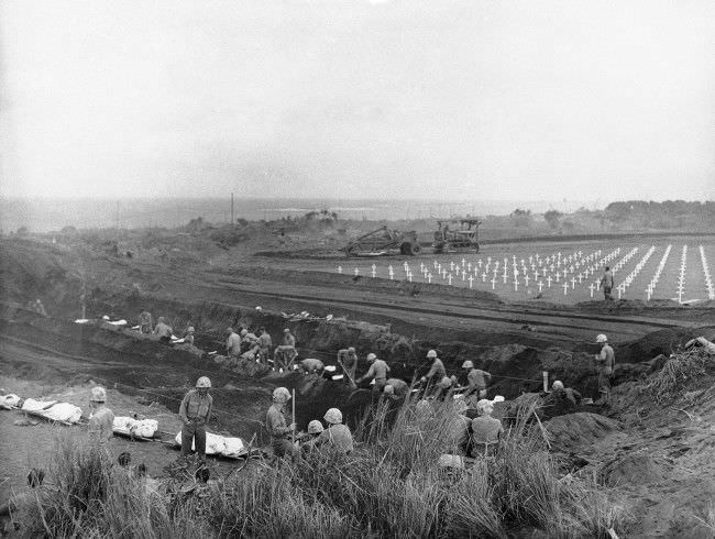 #43 U.S. Marines dig graves in the Fifth Marine Division cemetery on Iwo Jima, Japan, for the shrouded bodies of their buddies, 1945.