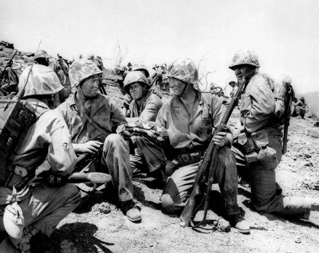 #47 In the movie reproduction of the flag raising scene on Iwo Jima, Capt. H.G. Schrier, left, who actually carried the flag up Mt. Surabachi, hands the flag to John Wayne, 1975.