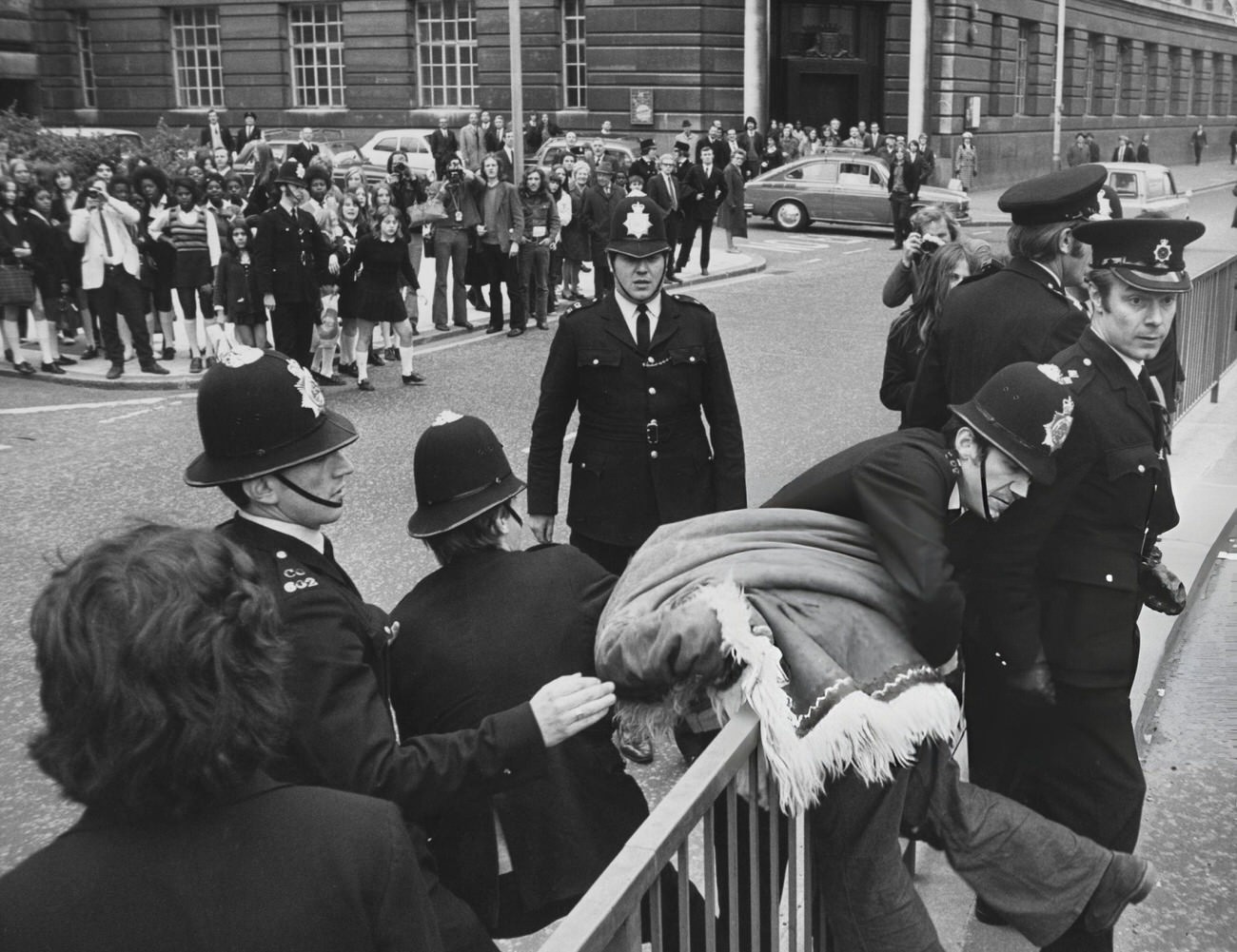 #20 Police officers restrain an Afghan-coated activist during a one-day strike organized by the Schools Action Union protest outside the Greater London Council headquarters at County Hall, 1972.