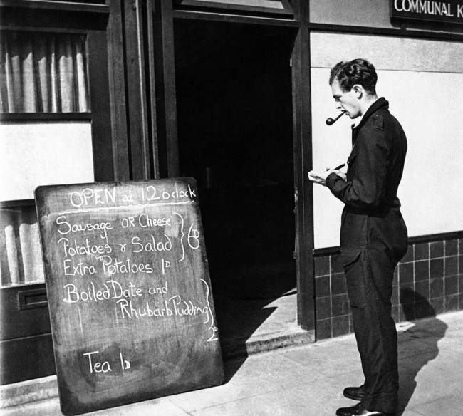#12 Christopher Ounsted, volunteer driver of the mobile canteen, stops at a communal kitchen to copy the days menu prior to starting out on his day’s rounds in London on Sept. 17, 1941. He presents a list of the food available to the people he visits, permitting them to make a selection.