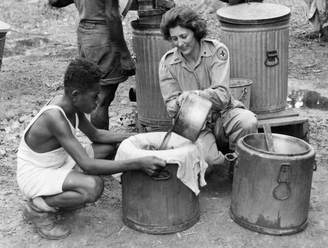 #24 Red Cross worker Marie Salcheider, of St. Paul, Minn., fills vats with freshly made coffee, at a base in Dutch New Guinea on Oct. 23, 1944. The coffee will be transported in mobile canteens to isolated areas.