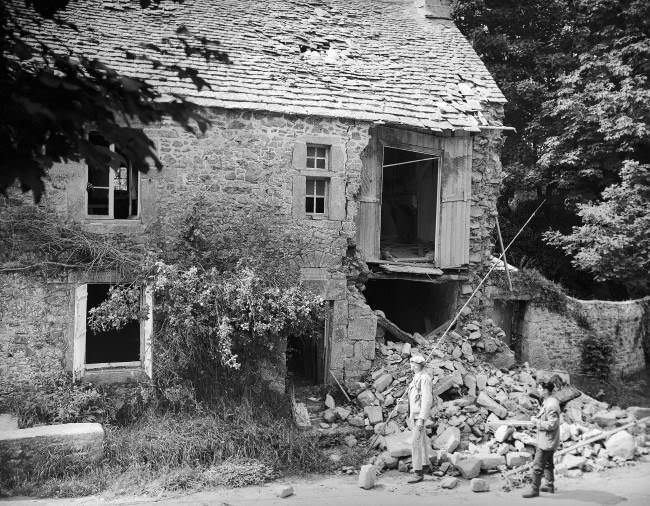#21 Two French civilians look over the wrecked birthplace of the French painter, Jean-Francois Millet in France, 1944. The house was situated at Gruchy near Greville, which was one of the most heavily fortified regions on the Normandy coast and the scene of many bitter battles before it was liberated by the Americans. Many Nazi soldiers were taken prisoner near here.