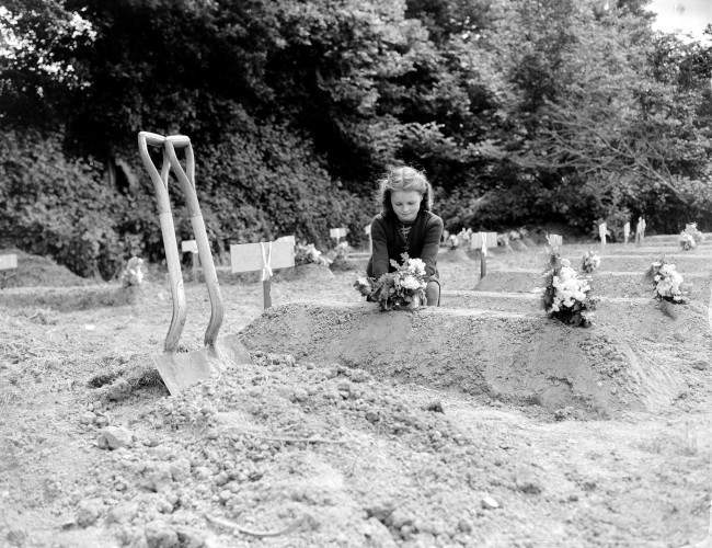 #9 A French girl places flowers over the freshly-dug grave of an American Airborne trooper as a token of appreciation of arrival of Allied liberators on the northern coast of France, 1944.