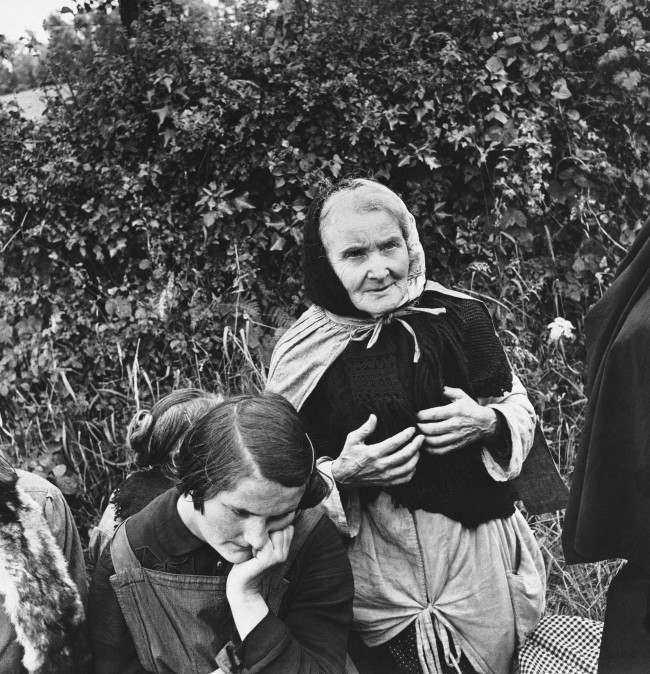 #40 An aged French woman, who fled from her home when the allies launched their attack on the Normandy peninsula of France, waits at a roadside with other refugees for the tide of war to pass so they can return to their homes, 1944.