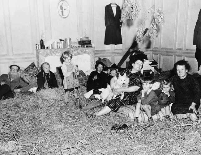 #42 Old and young, these refugees from the French town of St. Lo, in Normandy, 1944, take up temporary quarters in a former mansion following their return to the newly liberated town. Straw has been placed on the floor to provide a little comfort in the house that are being cared for by Allied Civil affairs authorities.
