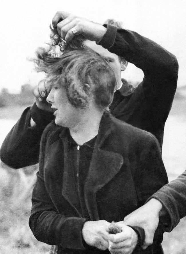 #10 Grande Guillotte, a 23 year-old French girl collaborated with the Germans in Normandy. When her town was liberated by Allied troops, French patriots dragged her from her house and cut off all her hair. A French patriot cuts off Grande Guillotte’s hair while another holds her in France, 1944.