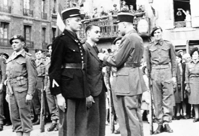 #11 The gendarme (left center) who led the first British troops into Bayeux, and a French underground leader, center, are decorated with the Croix de Guerre during Bastille Day ceremonies in a French city on the Normandy coast, France, 1944.