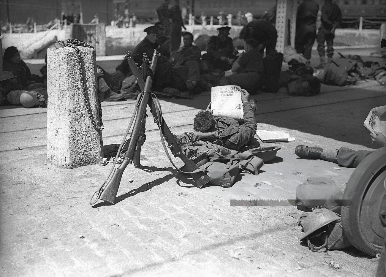 #26 A soldier reading his Daily Mirror newspaper following his evacuation from Dunkirk, 1940.